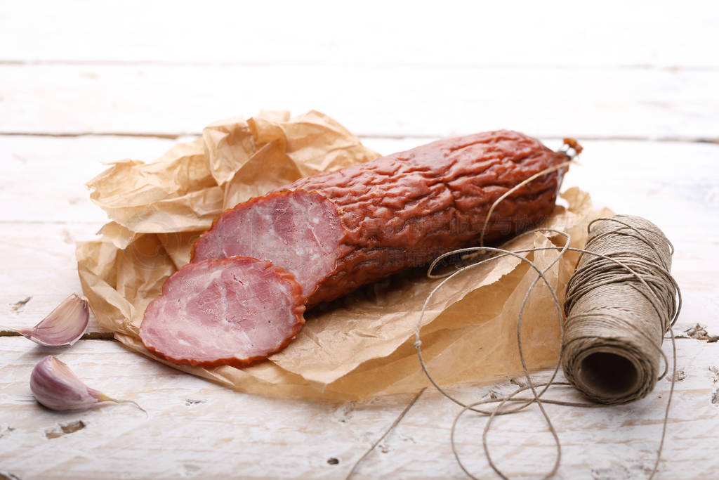 Traditional dry smoked pork sausage on a paper and wooden boards