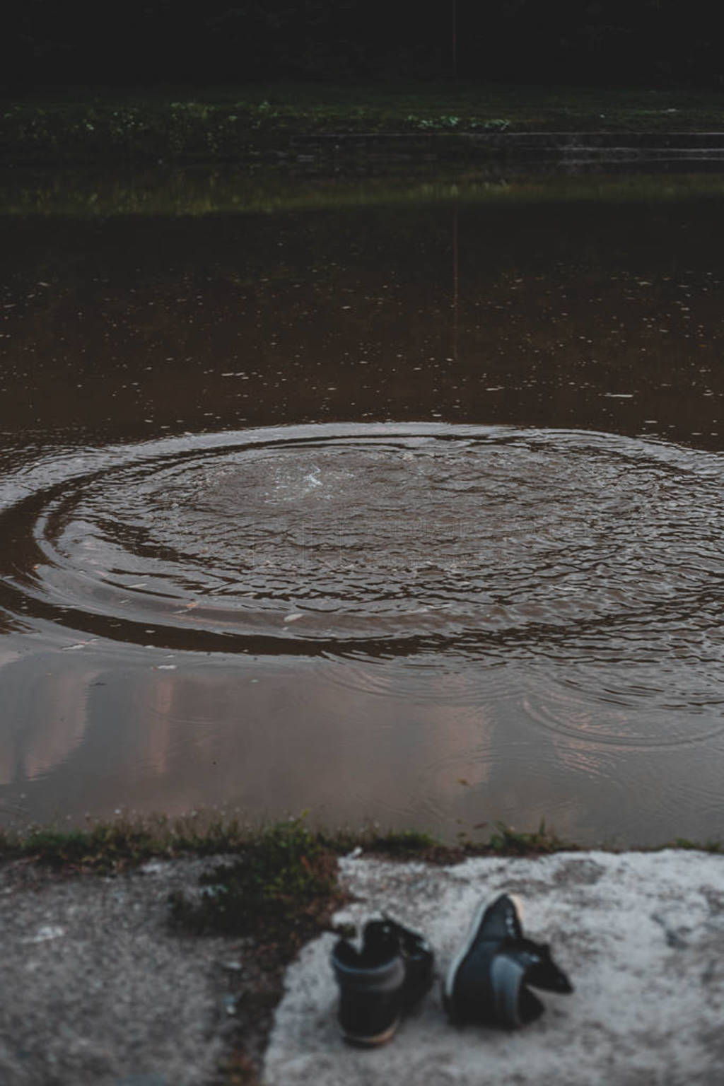 Empty shoes, sneaker on the river bank. Circles in water, after