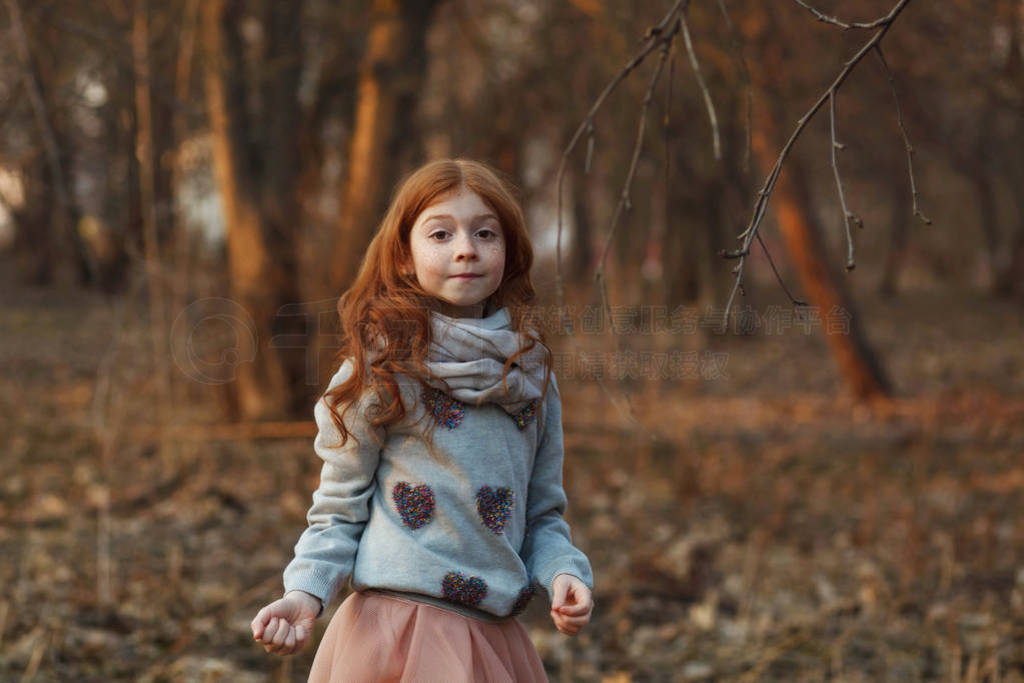 Portrait of a cute red-haired girl with freckles standing in an