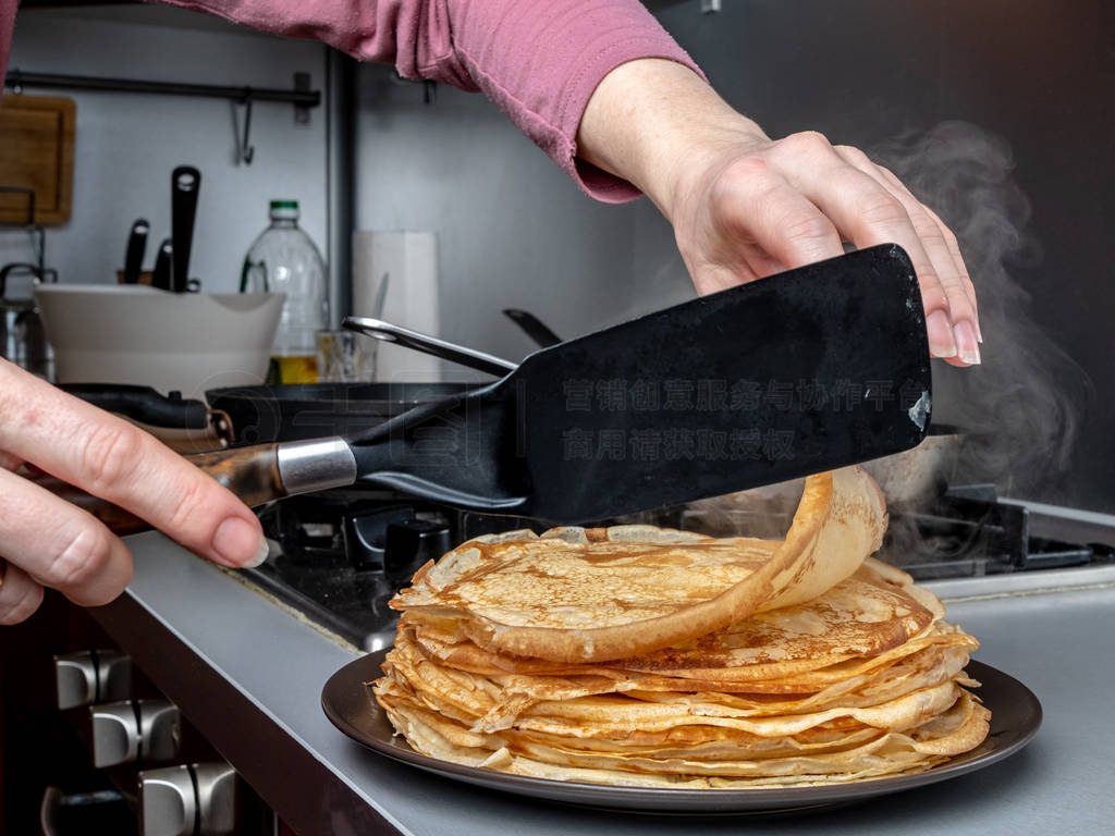 Human hands holding a kitchen spatula, spread on the dish a fres