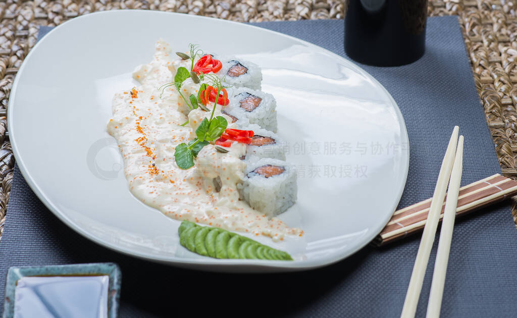 Traditional rolls with fish and rice on a white plate with sauce