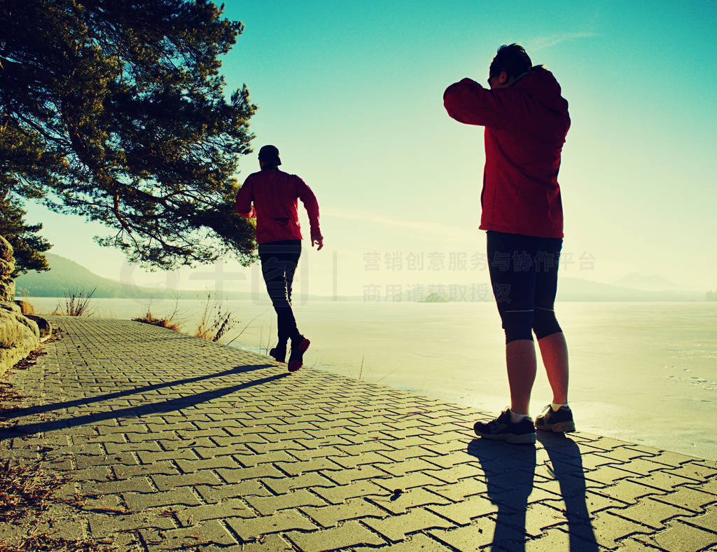 Man jogging at his girlfriend at river bank. Hills with hot Sun