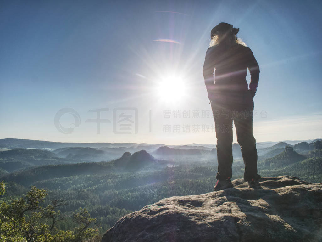 Hiker girl with leather cap stay with hands in pocket on cliff