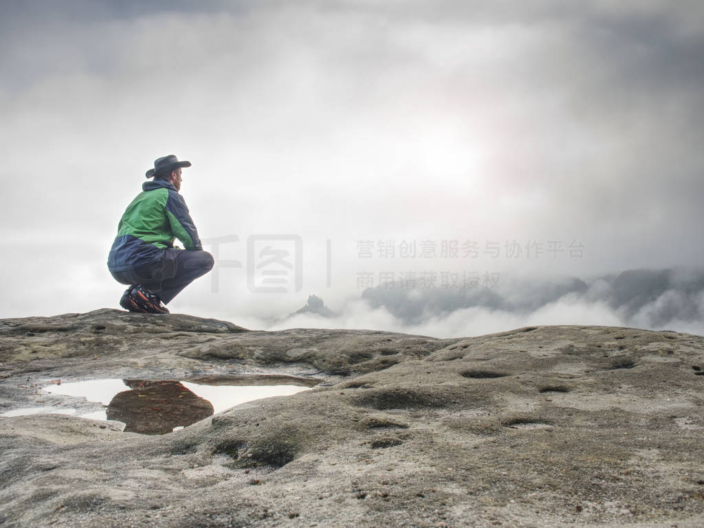 Lonely man sit on cliff enjoy the view over valley full of mist