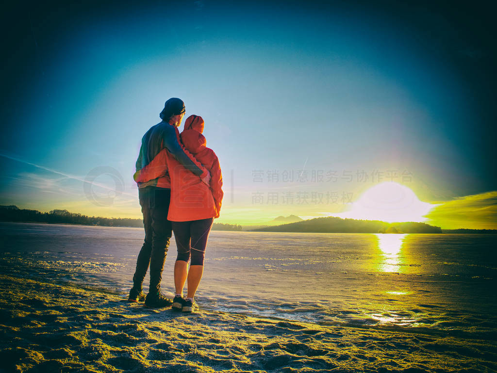 Couple in love stay at snow covered ice on the lake.