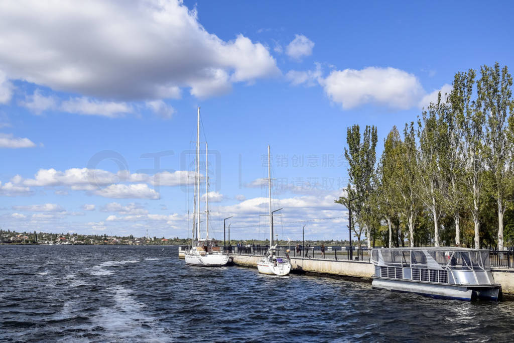 Small sailing yachts and pleasure catamaran are moored at the ci