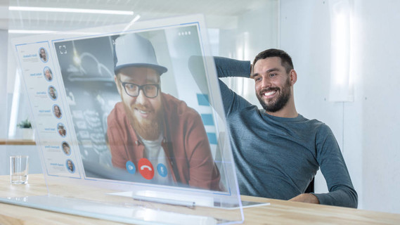 在不久的将来, 男人用电脑给他的朋友做视频通话。他们有友好的聊天。办公设计现代明亮