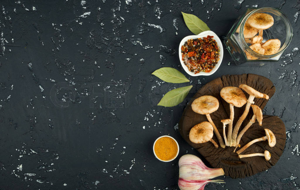 Fresh mushrooms with spices and herbs on black board. View from