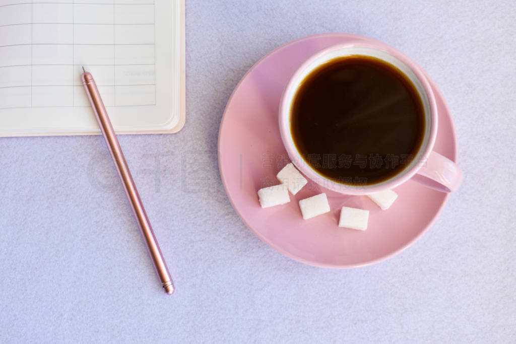 Pink cup black of coffee, notebook, pen. Overhead view.