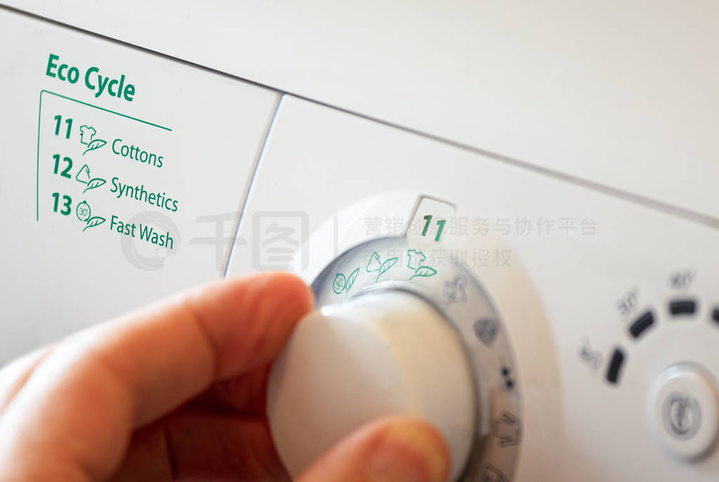 Close up of hand selecting green eco cycle on washing machine.