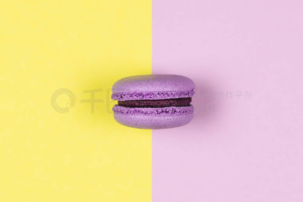 Purple french macaron on a yellow and purple background.