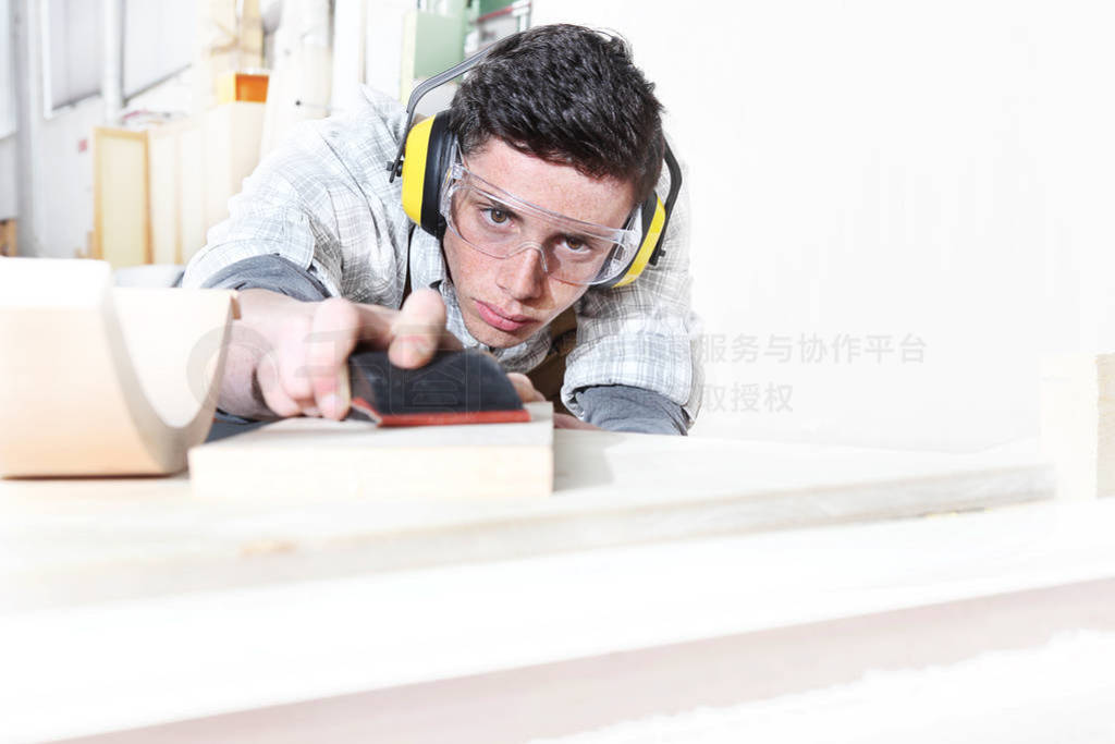 carpenter man work in the carpentry, sanding wooden boards with