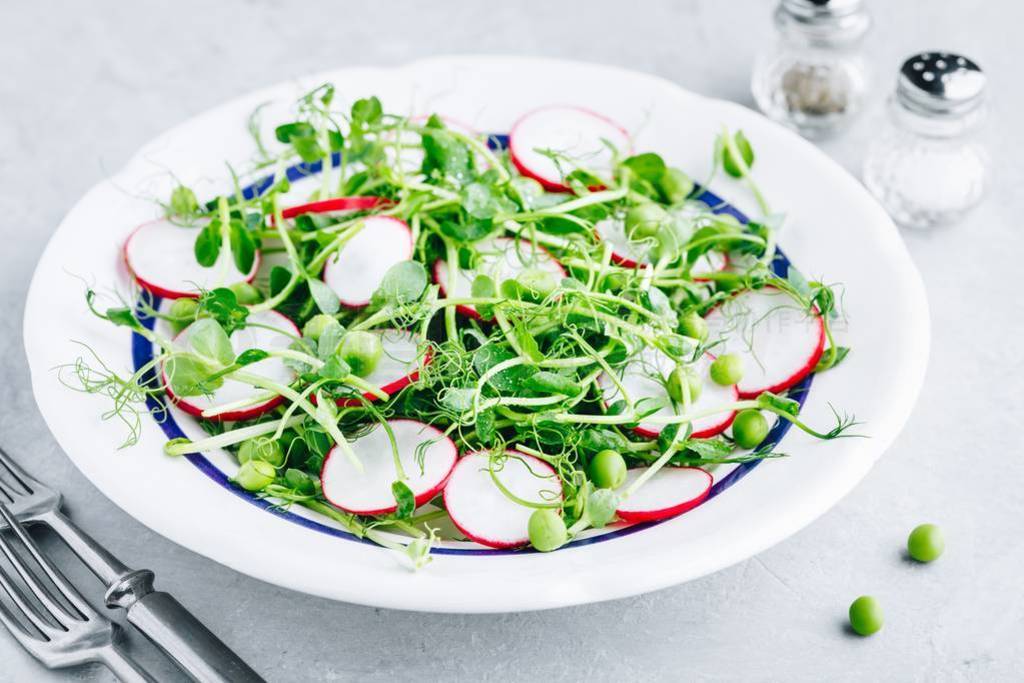 Fresh green pea shoots salad with radishes.