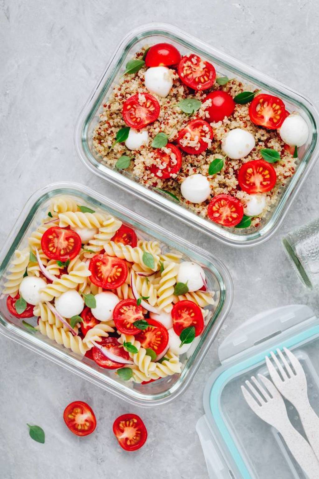 Meal prep containers with pasta salad or quinoa, tomatoes, mozza