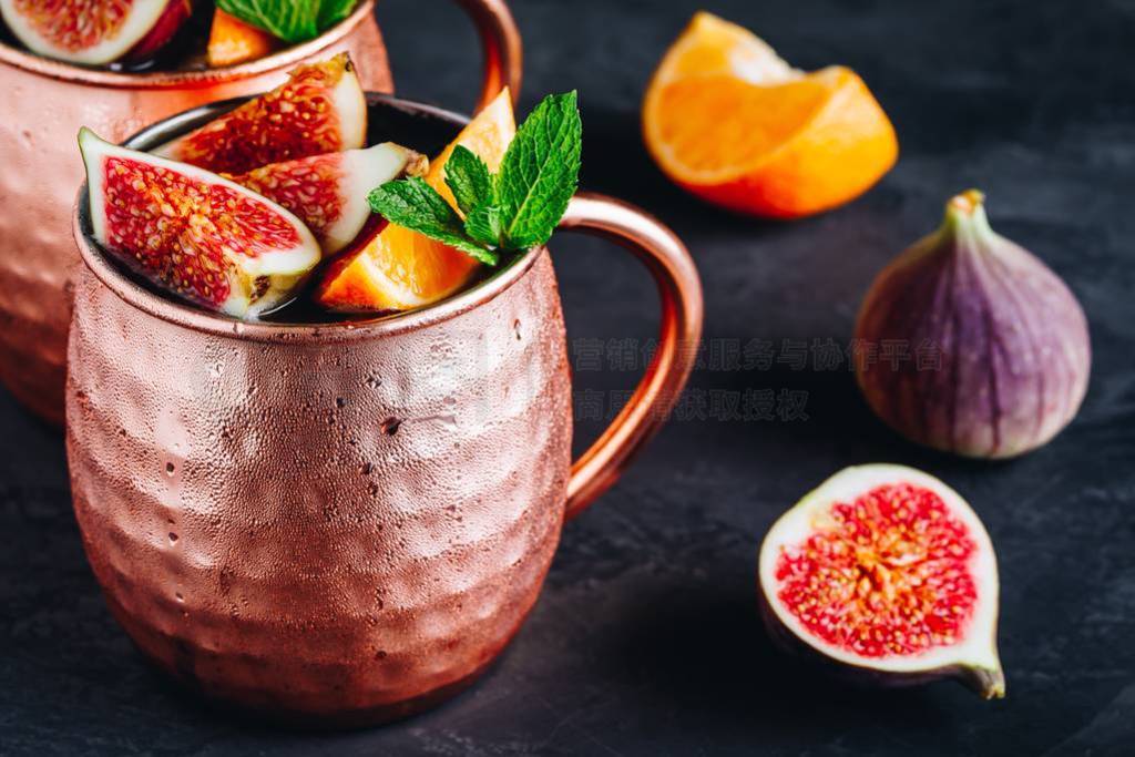 Fig moscow mule ice cold cocktail in copper cup with oranges and