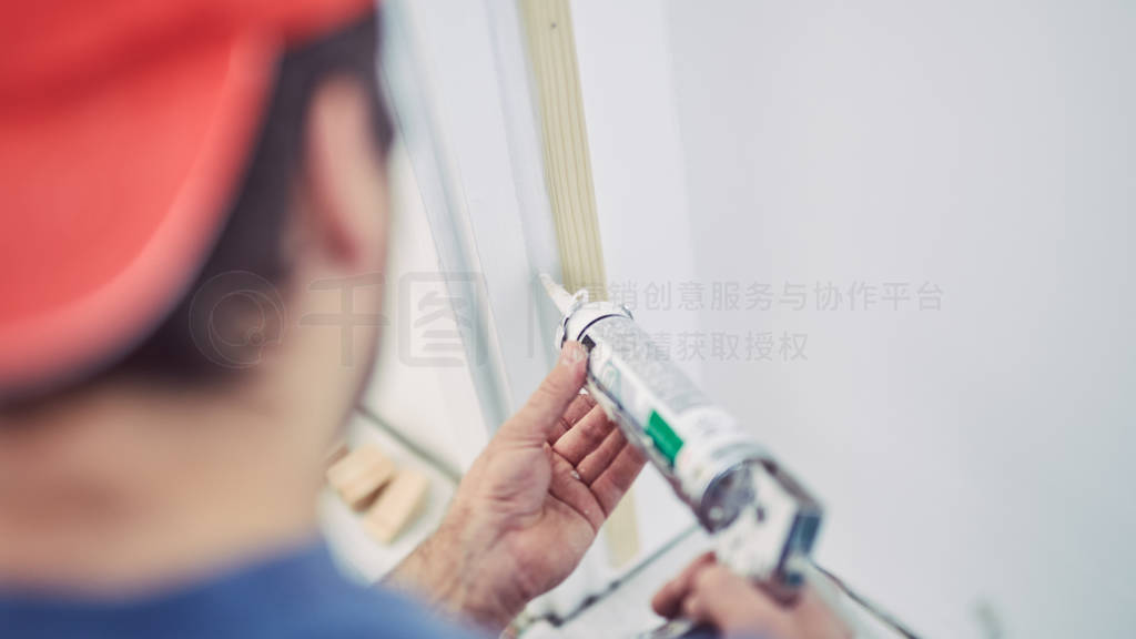 Worker using silicone for walls and door frame inside the house