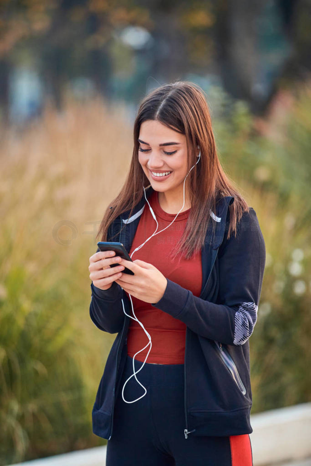 Modern young woman with cellphone making pause during jogging /