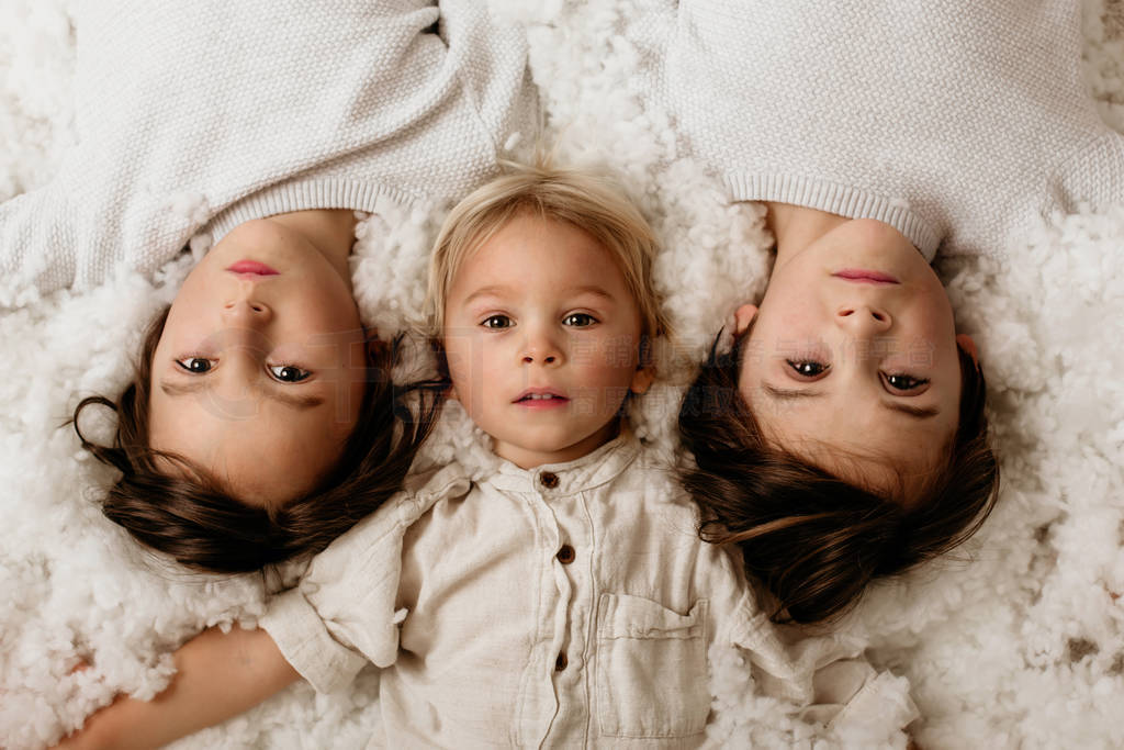Beautiful portrait of three sibling boys, lying on the floor in