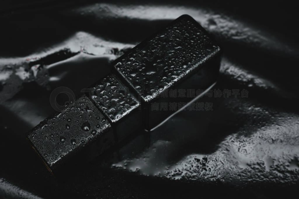 wet black perfume on dark background