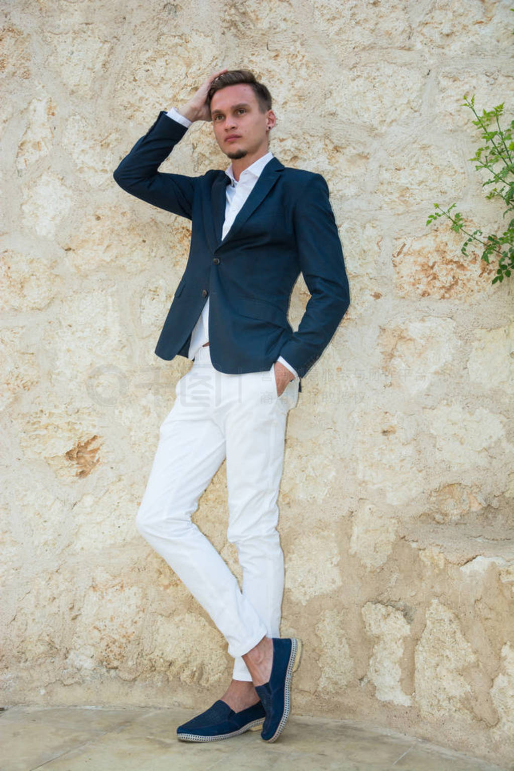 Young handsome man in a suit and white pants at standing near a