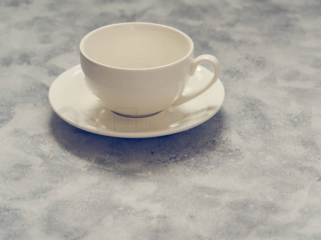 Empty white cup with saucer on a gray concrete background