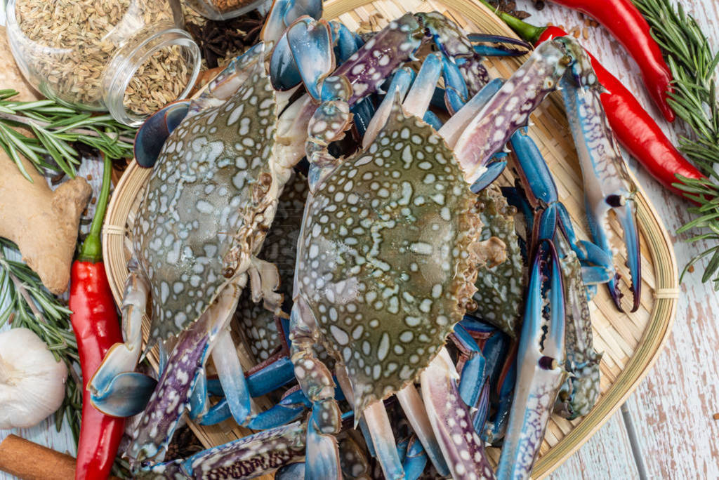 Fresh Raw Crab surrounded by spices and ingredients on a wooden