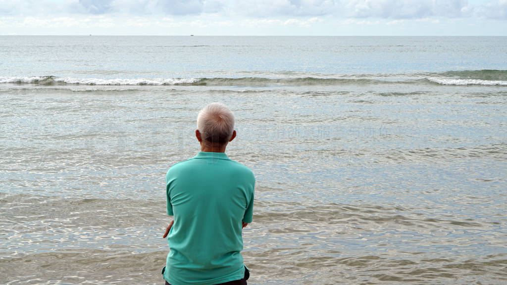 Elder senior Asian man sitting alone at ocean coastline