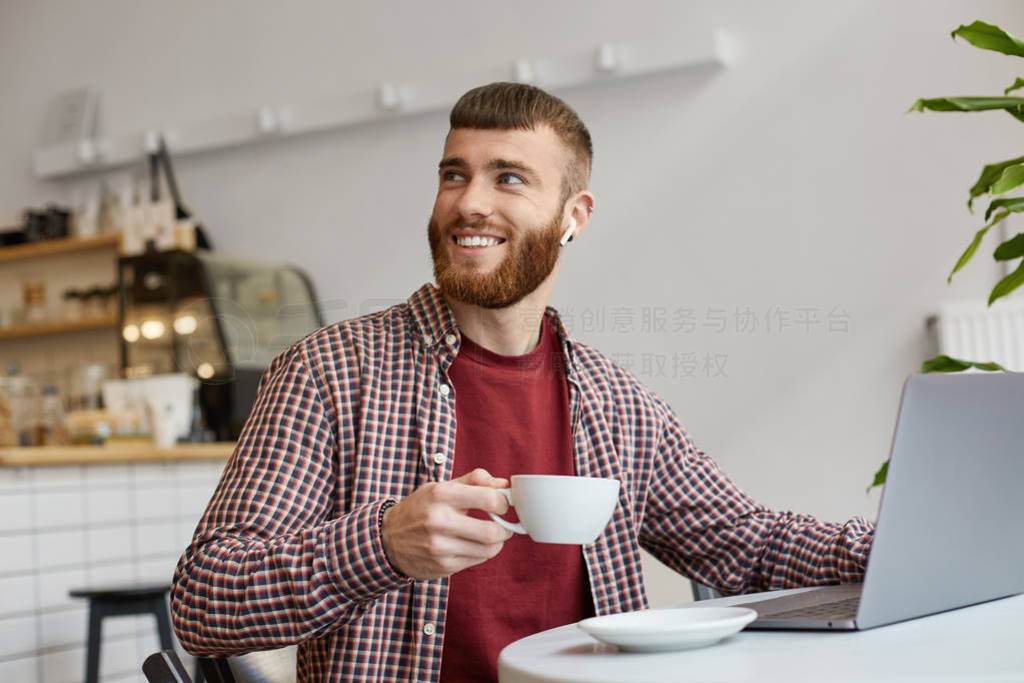 Photo of happy smiling attractive ginger bearded man working at