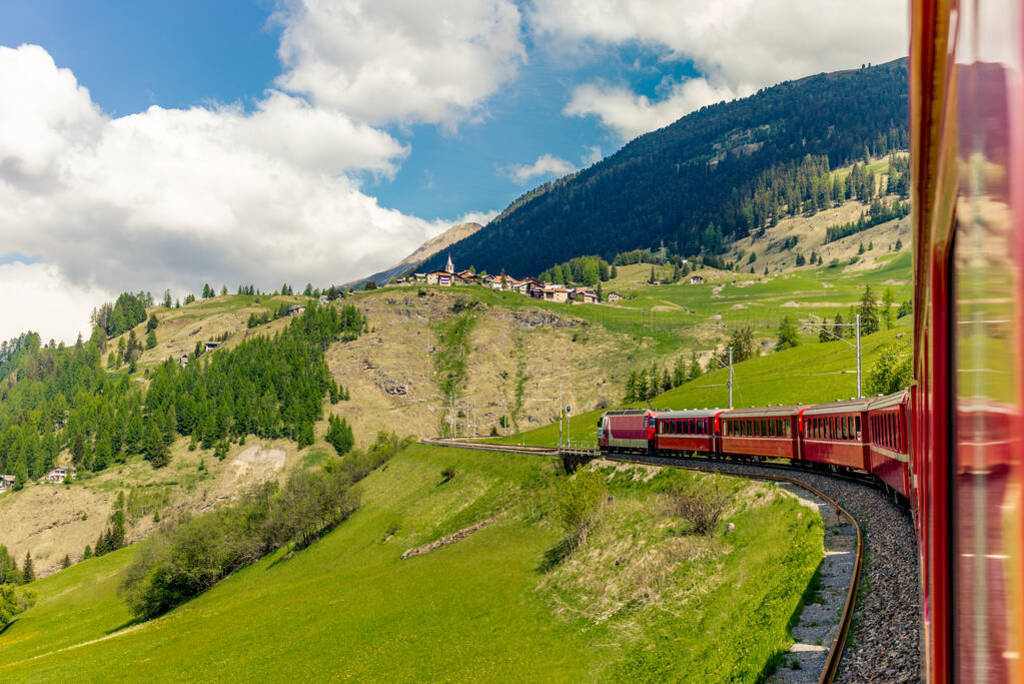 Red train slowly climbing to the Bernina Pass in the Swiss Alps