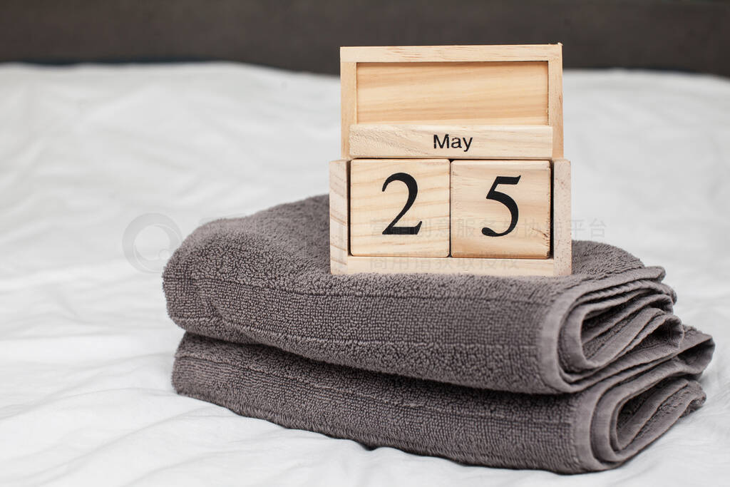 Gray terry towels on the bed with white linens and a wooden cal