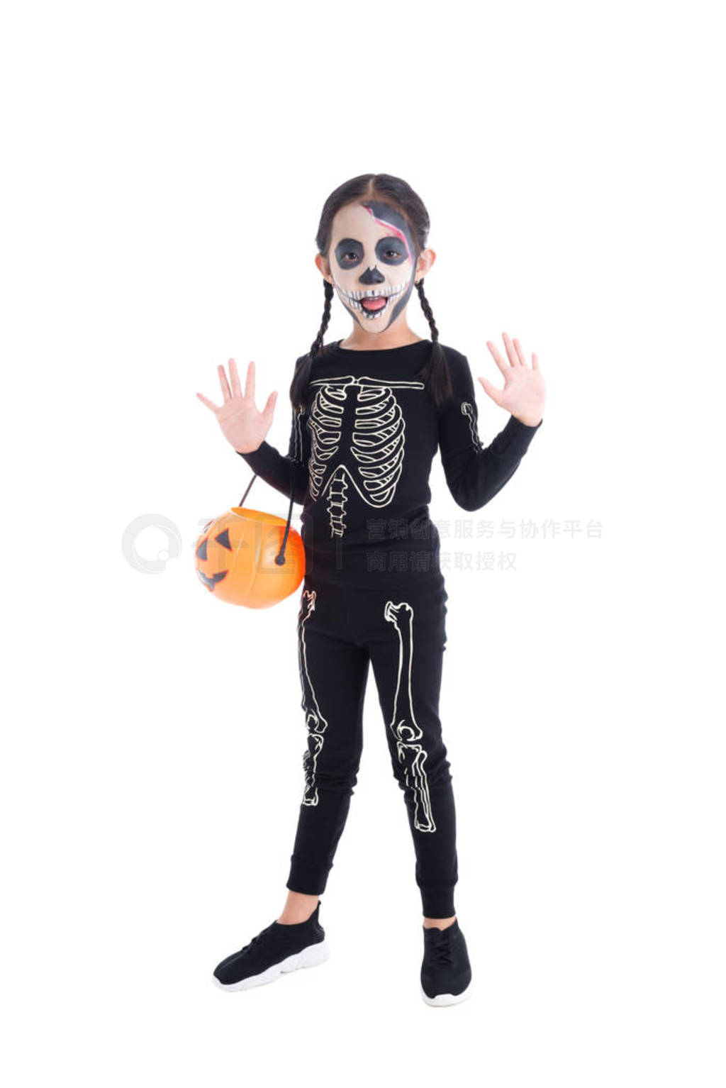 Full length of girl in skeleton costume holding halloween pumpki