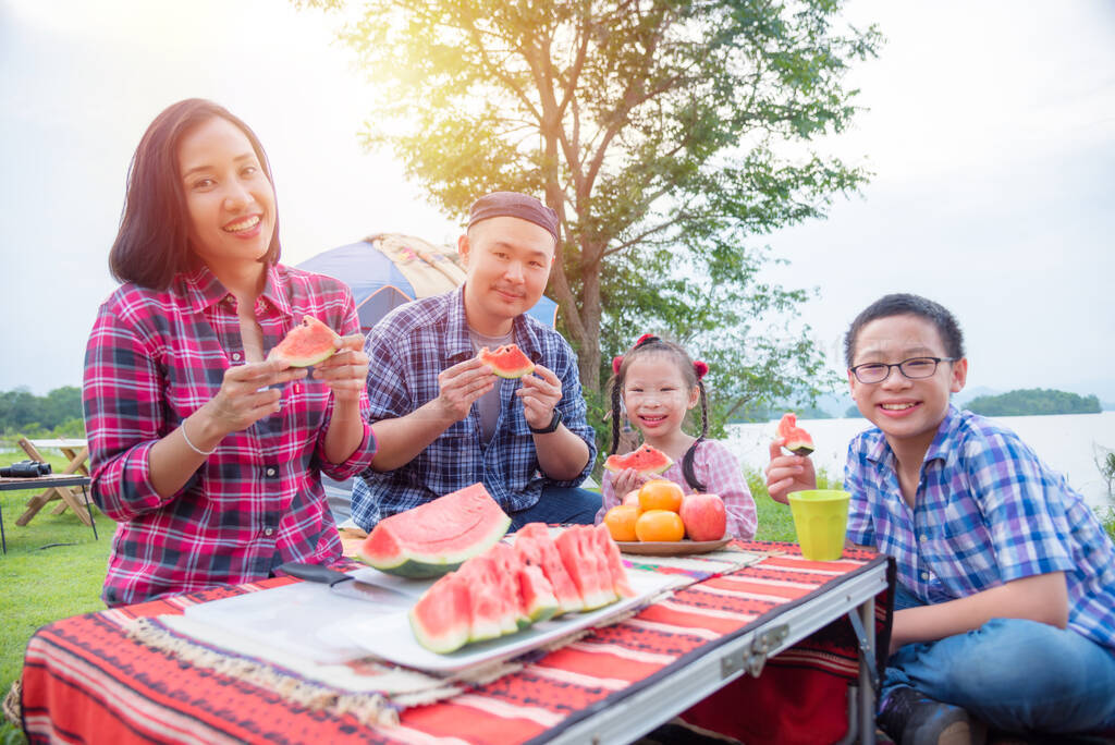 Group of asian family camping at lakeside, everyone holding a sl