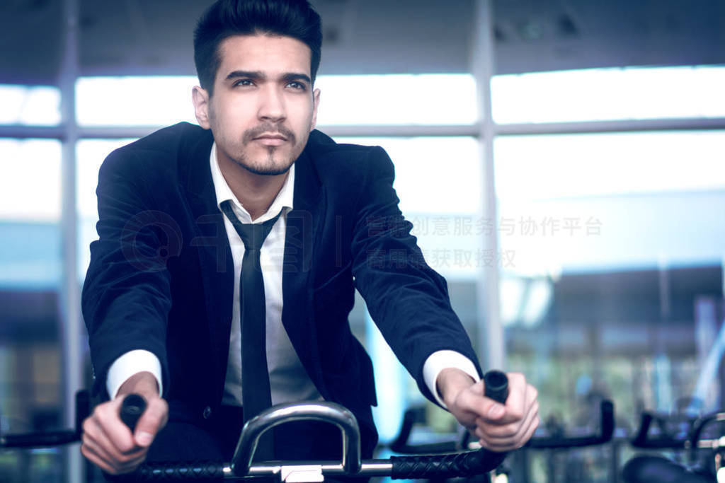 Businessman in white shirt and suit on a stationary bike in the