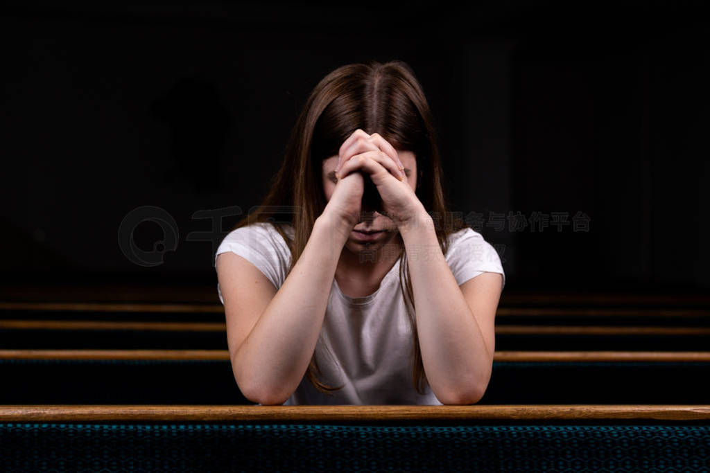 A Sad Christian girl in white shirt is sitting and praying with