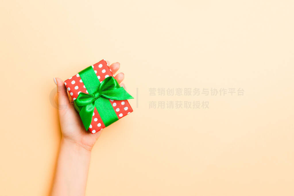 Flat lay of woman hands holding gift wrapped and decorated with