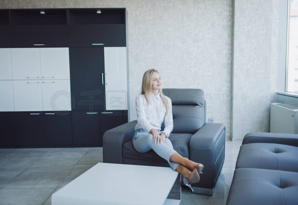 confident blonde in suit sit in chair