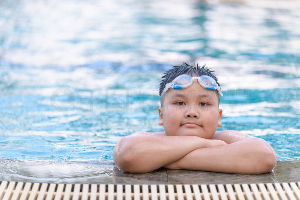 Obese fat boy wear goggle and smile in swimming pool,
