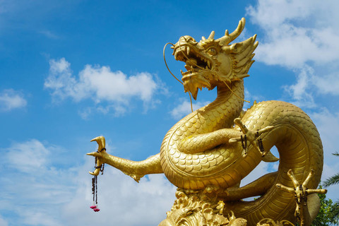 在普吉岛到蓝蓝的天空背景上的金色中国龙雕像