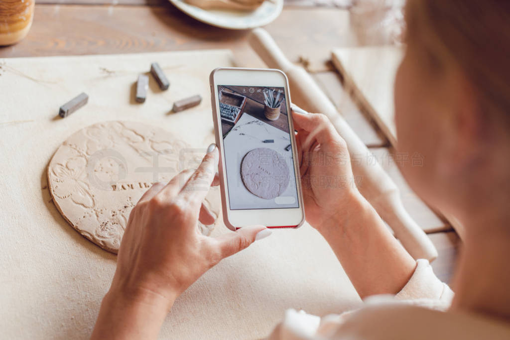 Woman makes a photo of her work from clay with the words