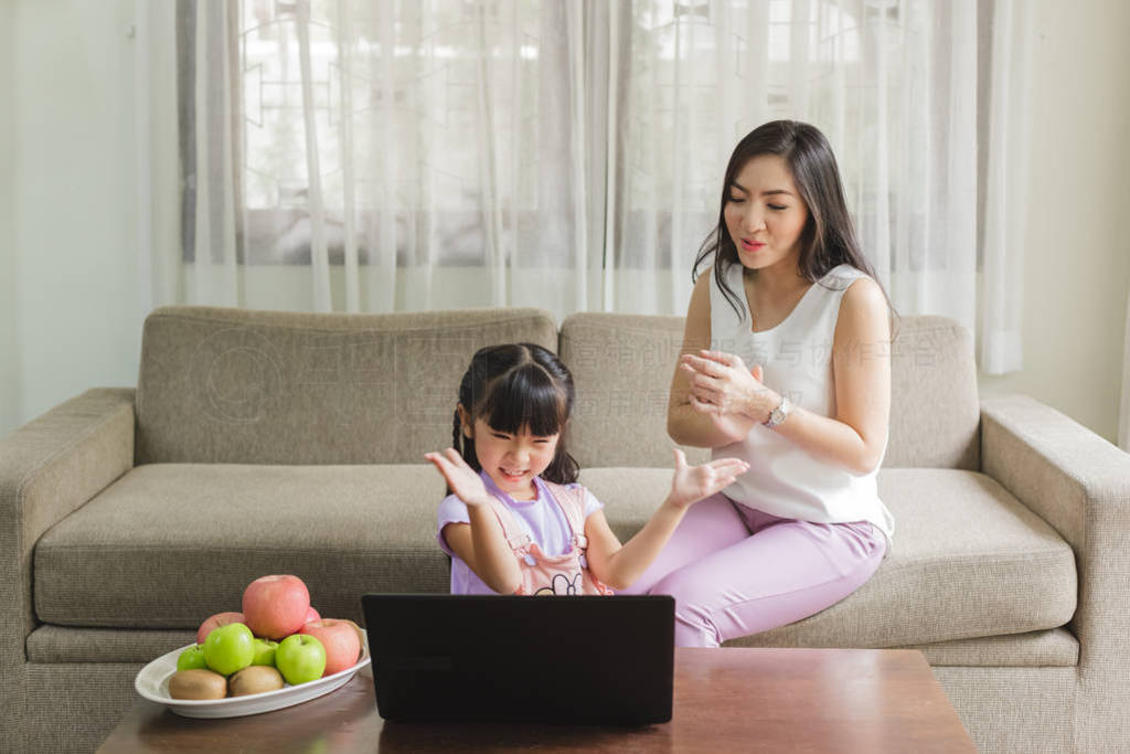 Mother and daughter using laptop with funny together at home.