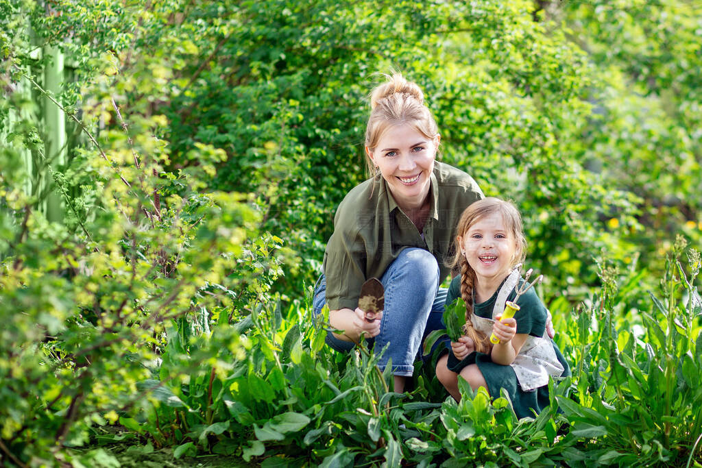 Mother and daughter in the garden harvest. A young blonde woman