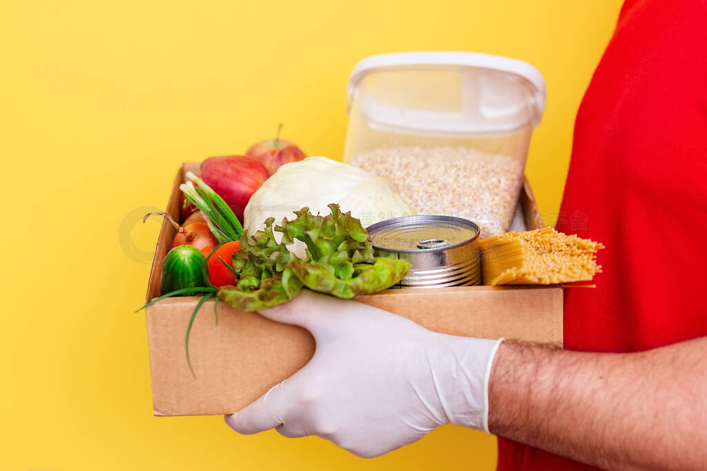 A volunteer brings a box of food. Fresh vegetables and groceries