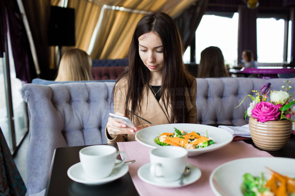 Beautiful girl in a cafe with a phone in her hands. Close-up, si