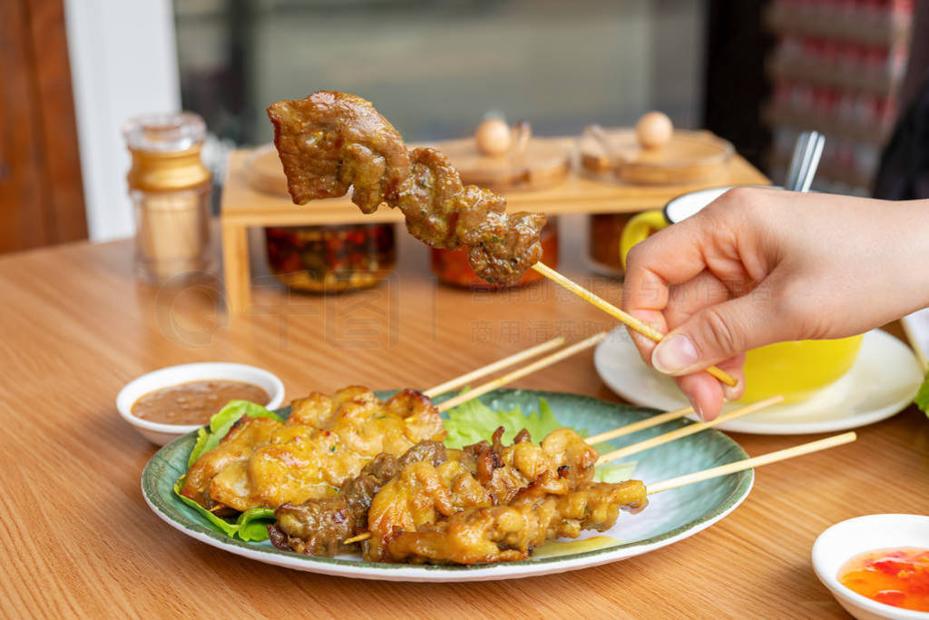 Woman hand holds a Pieces of satay