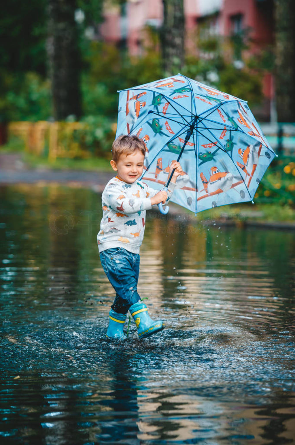 Child with umbrella walking in puddle on rainy weather.