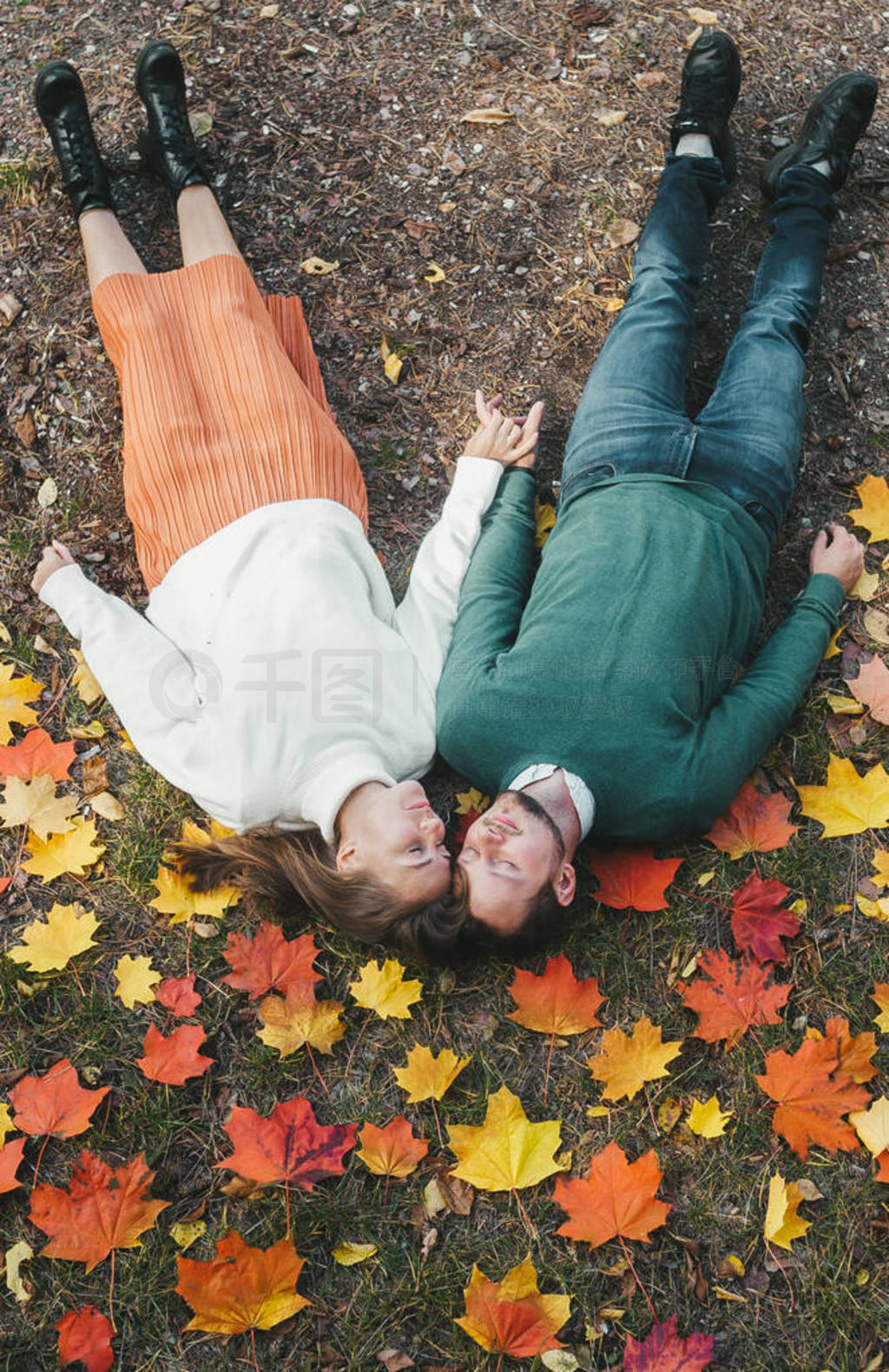 Top view young joyful happy couple in love lying on fallen leave