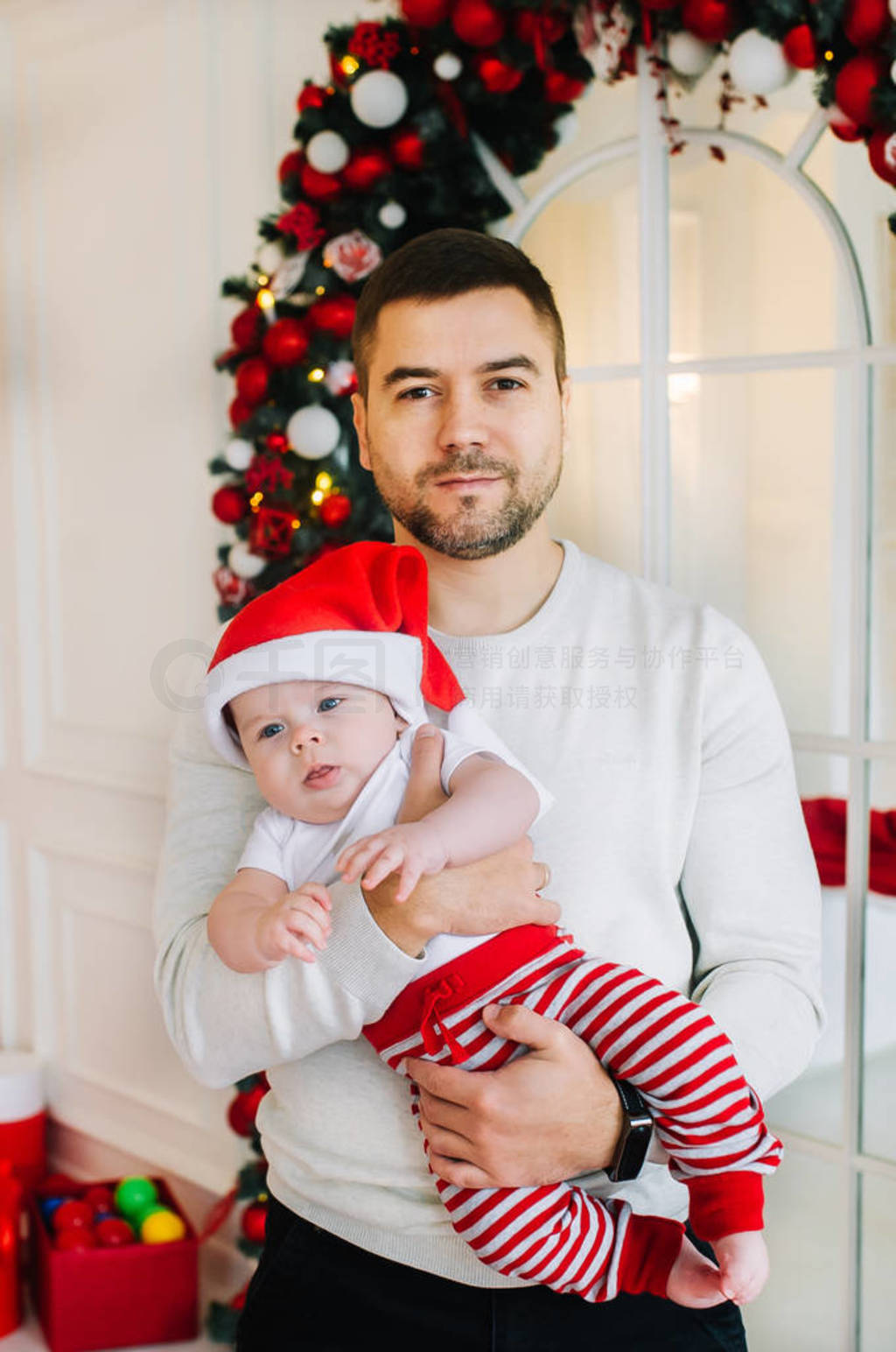 Dad and his baby son in Santa cap indoors.