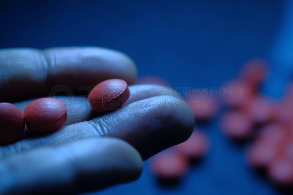 Close up of red pills on man hand, drug abuse concept