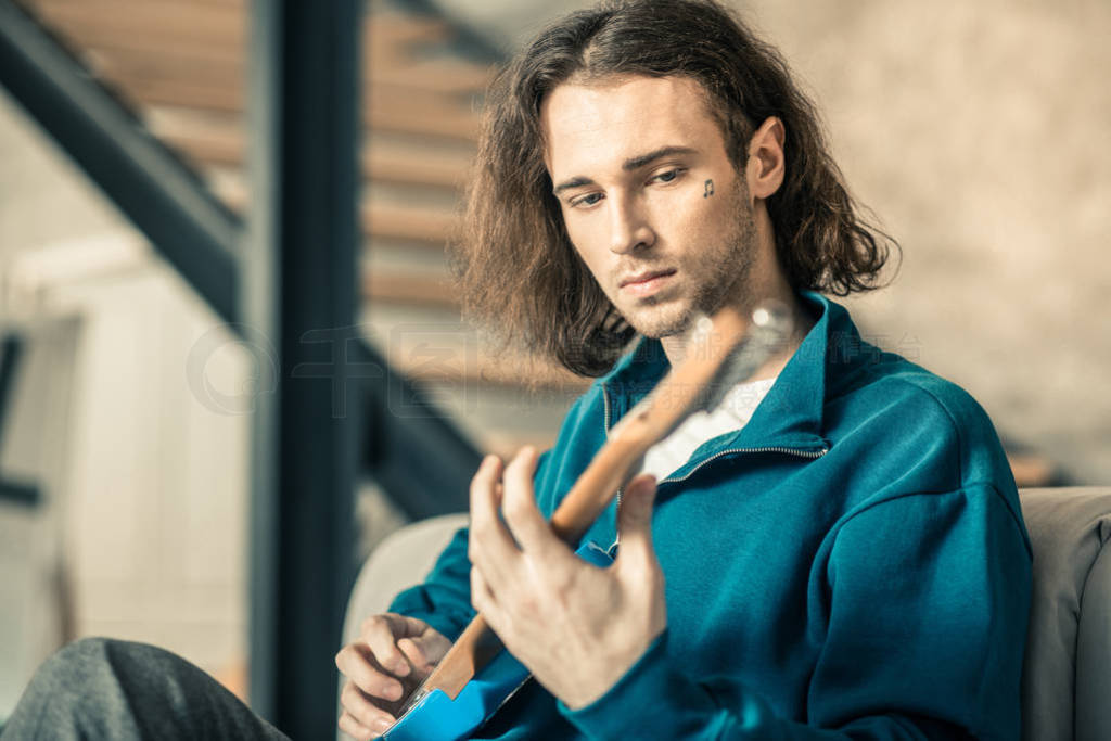 Emotionless long-haired unusual guy starting his musical repetit