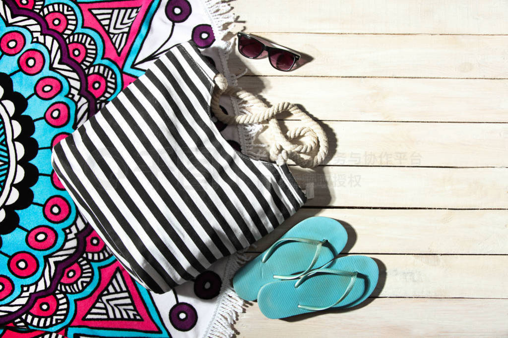 Striped bag, rubber flip flops and bright beach towel